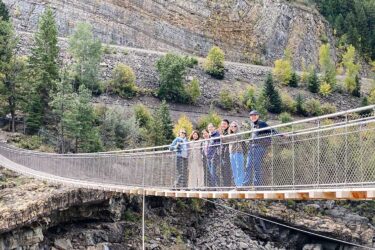 a group of international students smiling on posing on the kootenai falls bridge