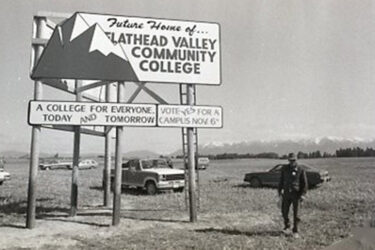 a man stands next to a sign reading future home of flathead valley community college