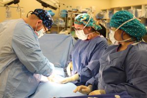 surgical technology students wearing scrubs conduct a mock operation in a classroom