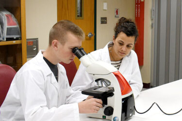 two students work with a microscope