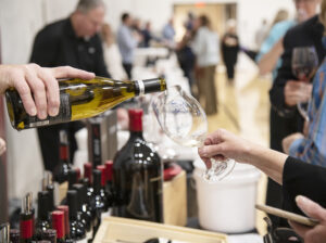 serving wine to guests at the light the night festival of flavors event for student scholarships