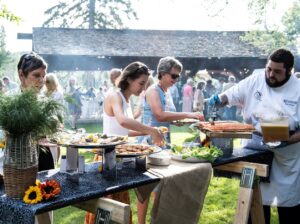 a culinary student serving guests at a sunny outdoor event