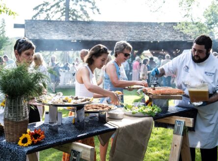 a culinary student serving guests at a sunny outdoor event