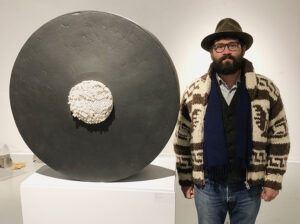 artist Jospeh Pesina standing next to one of his ceramic artworks
