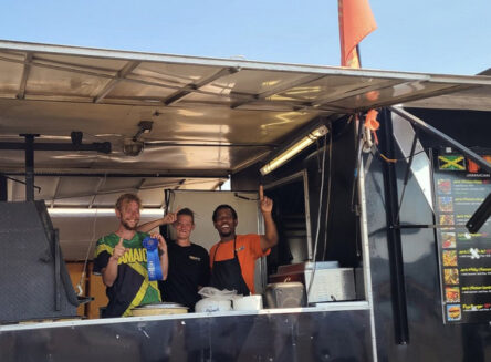 fiya grill staff pose in their food truck holding a blue first place ribbon