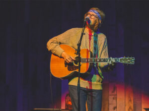 brett dennen playing guitar and singing on stage