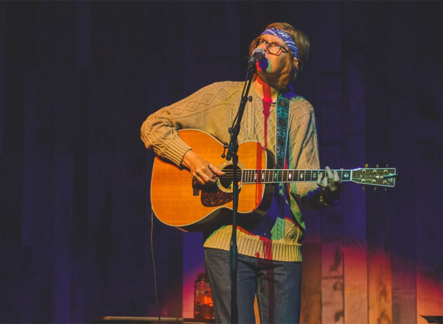 brett dennen playing guitar and singing on stage
