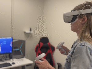 person in virtual reality headset and controls in FVCC's Makerspace