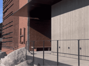 Modern alpine architecture of the Larch House in Whitefish, featuring a dark metal exterior with a prominent vertical design element and warm wood paneling.