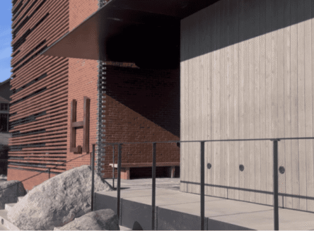 Modern alpine architecture of the Larch House in Whitefish, featuring a dark metal exterior with a prominent vertical design element and warm wood paneling.